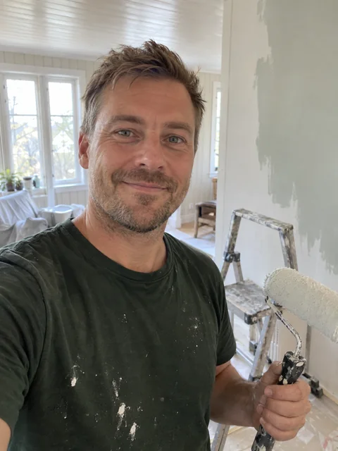 Sindre Solberg Aas med malerull midt i oppussingen av trehuset på Byåsen